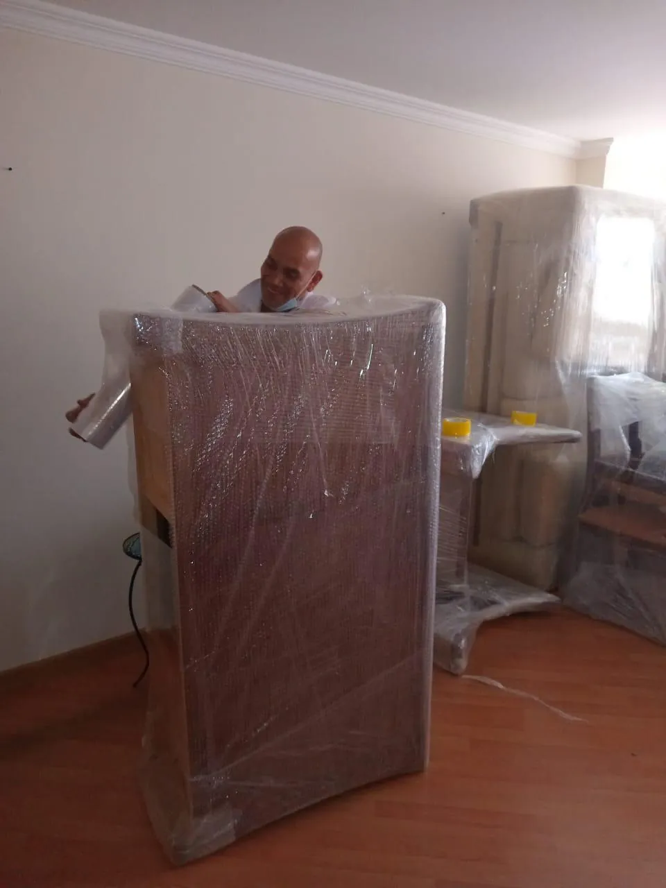 Técnico de Mudanzas Jireh embalando un mueble con plástico protector
