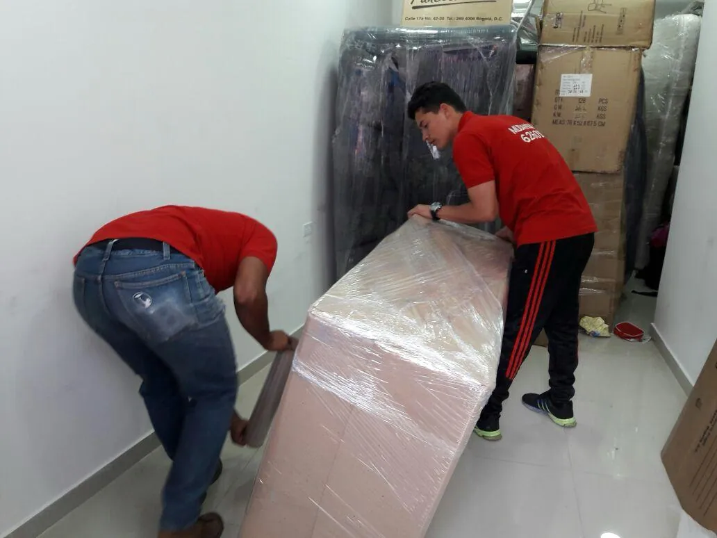 Equipo uniformado de Mudanzas Jireh cargando un mueble embalado dentro de una vivienda